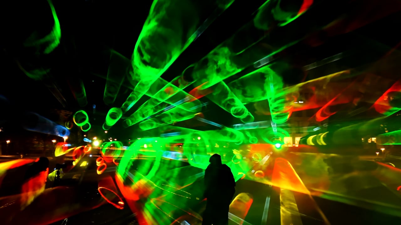 Visitors standing inside ÆTHER, a walk-in installation of green, magenta and blue light beams in fog at the Marx-Engels-Forum in Berlin