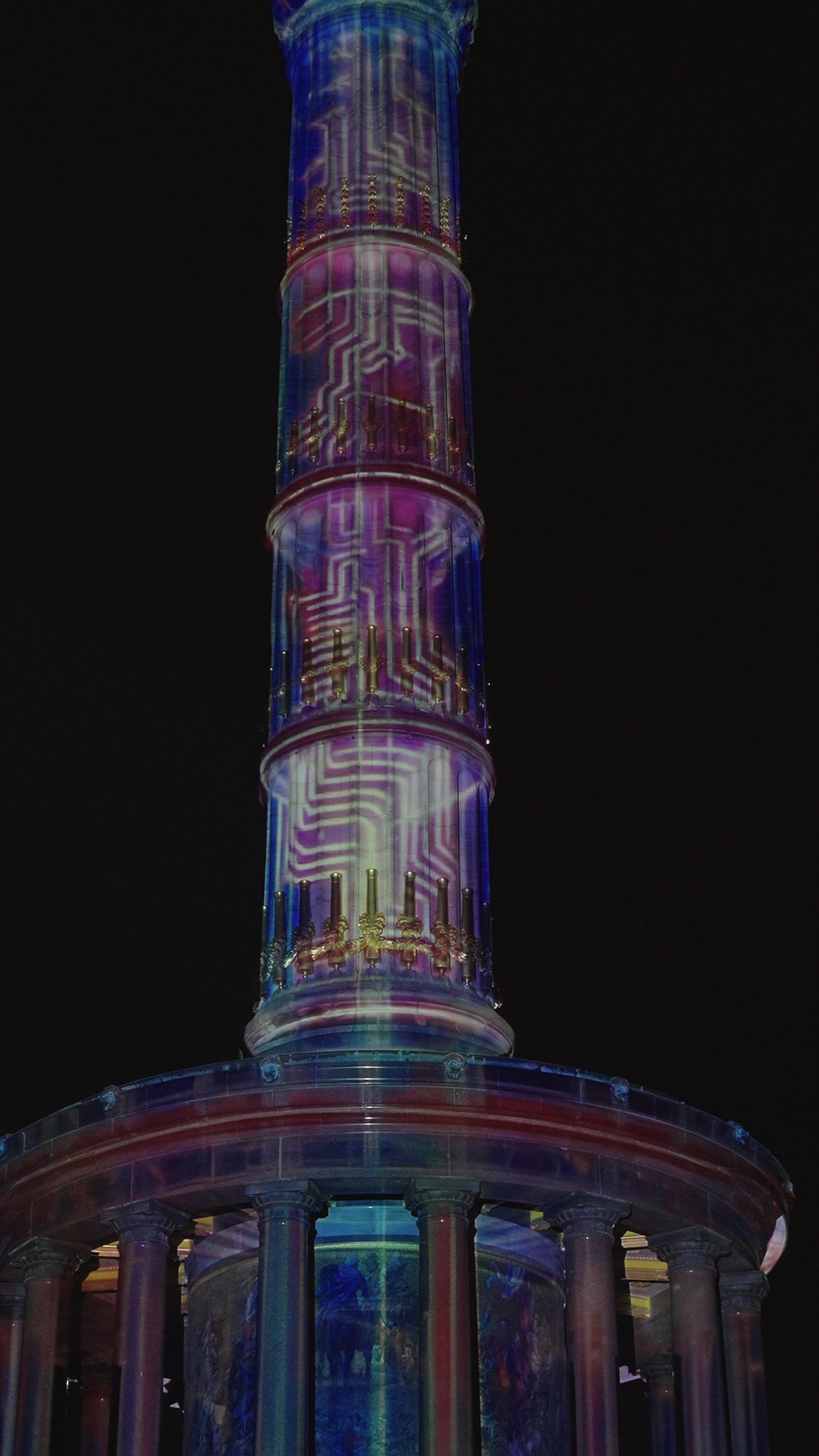 The Berlin Victory Column wrapped in a rainbow-coloured 360-degree projection mapping at night, filmed from below